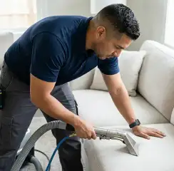 Professional upholstery cleaning technician using an extraction wand to deep-clean a fabric sofa, Tucson, AZ.