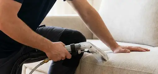 Professional upholstery cleaner deep-cleaning a fabric sofa with a handheld extraction tool, Tucson, AZ.